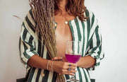 Person holding a glass of pink wine and a bundle of lavender.