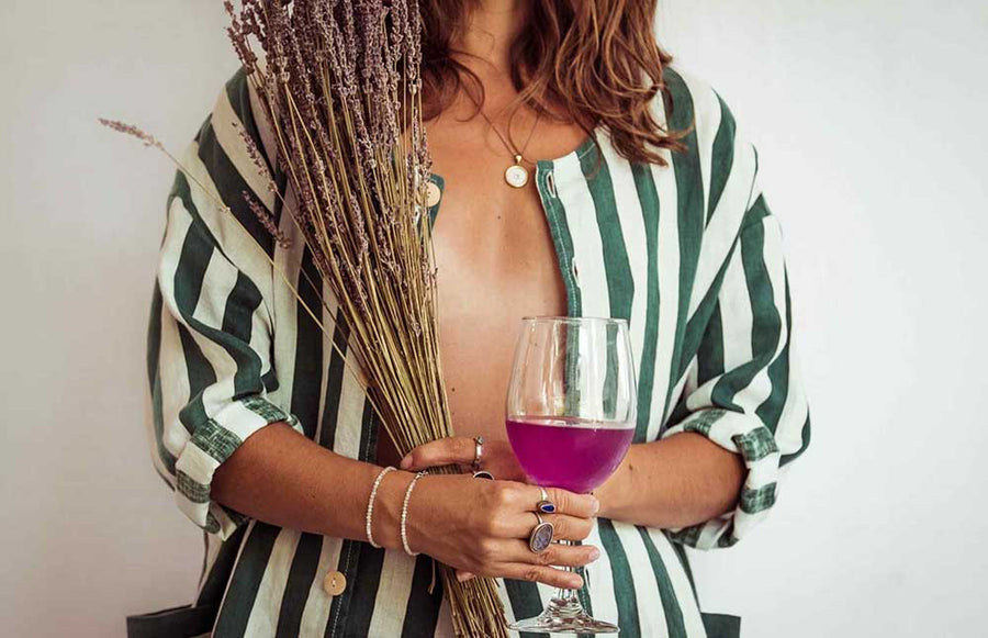 Person holding a glass of pink wine and a bundle of lavender.