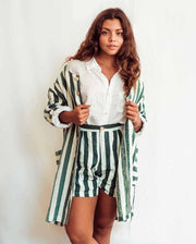Woman wearing a white shirt and green striped shorts with a matching jacket against a white background