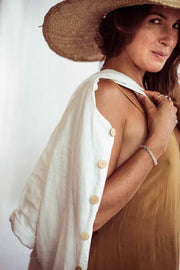 Woman wearing a straw hat and a white shirt over a yellow dress on a plain background