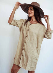 Woman wearing a beige dress and brown hat against a white background