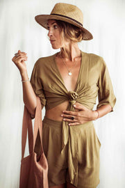 Woman wearing a beige outfit with a hat against a white background