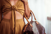 Person wearing a mustard yellow outfit with a patterned handbag.