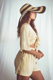 Woman wearing a yellow outfit and large sun hat against a white background