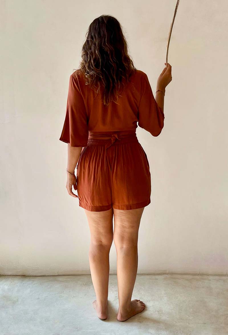Person wearing a brown romper against a plain background