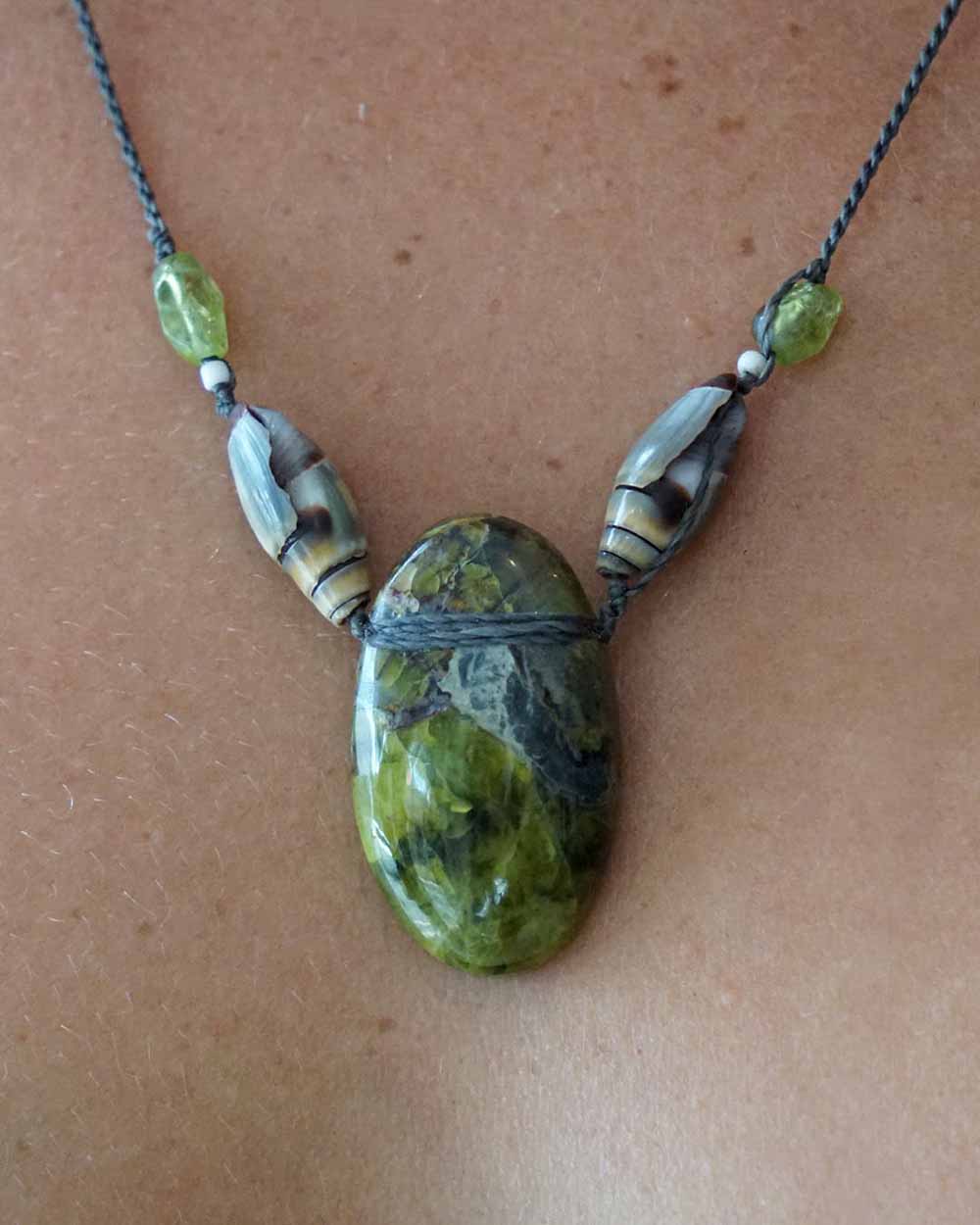 Necklace with a large green stone pendant on a brown surface