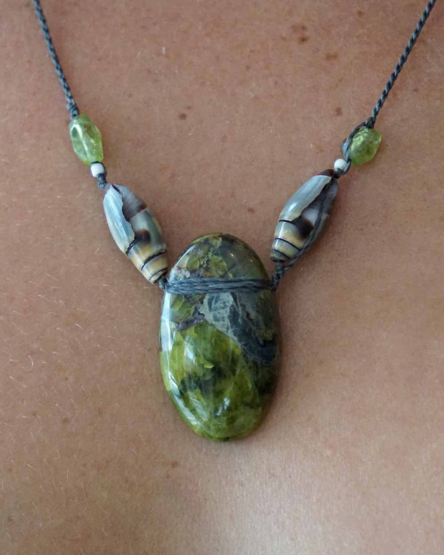 Necklace with a large green stone pendant on a brown surface