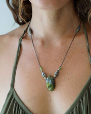 Necklace with a large green stone pendant worn by a person in an olive green top.