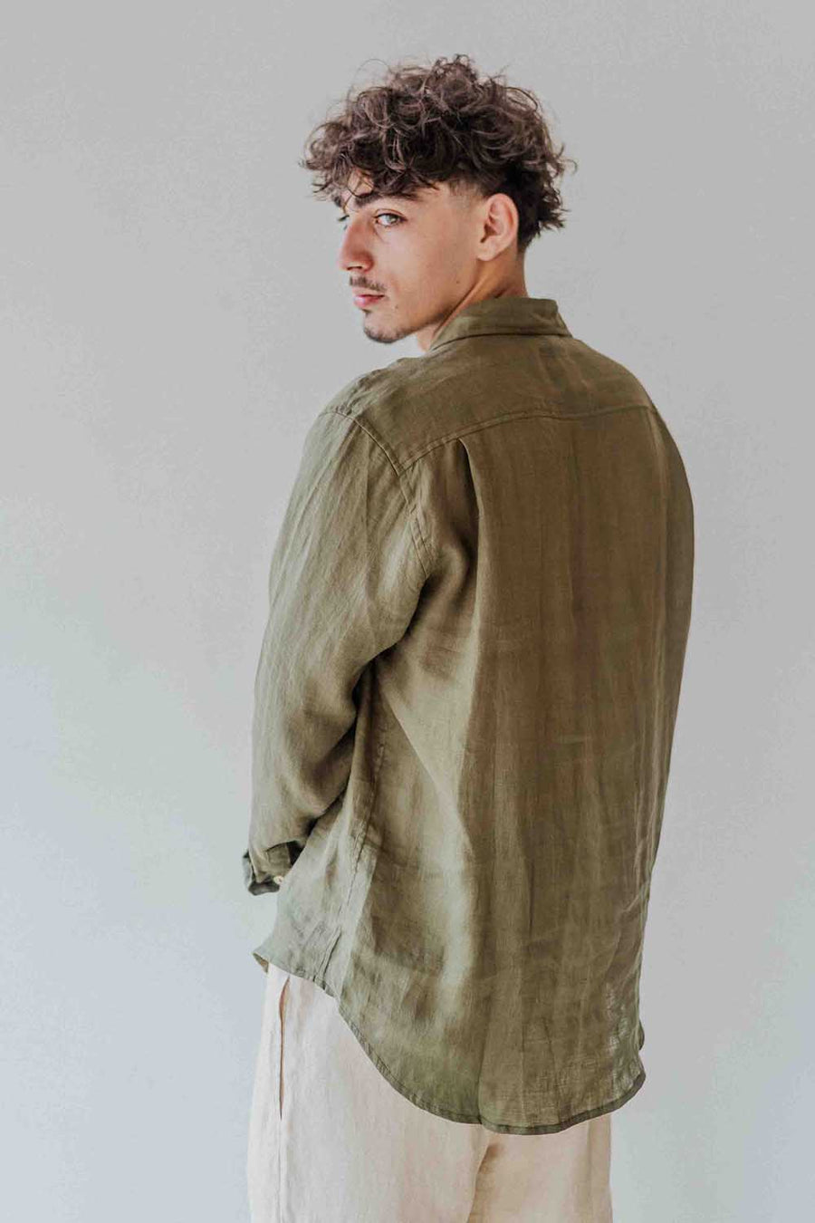 Person wearing an olive green jacket against a plain background