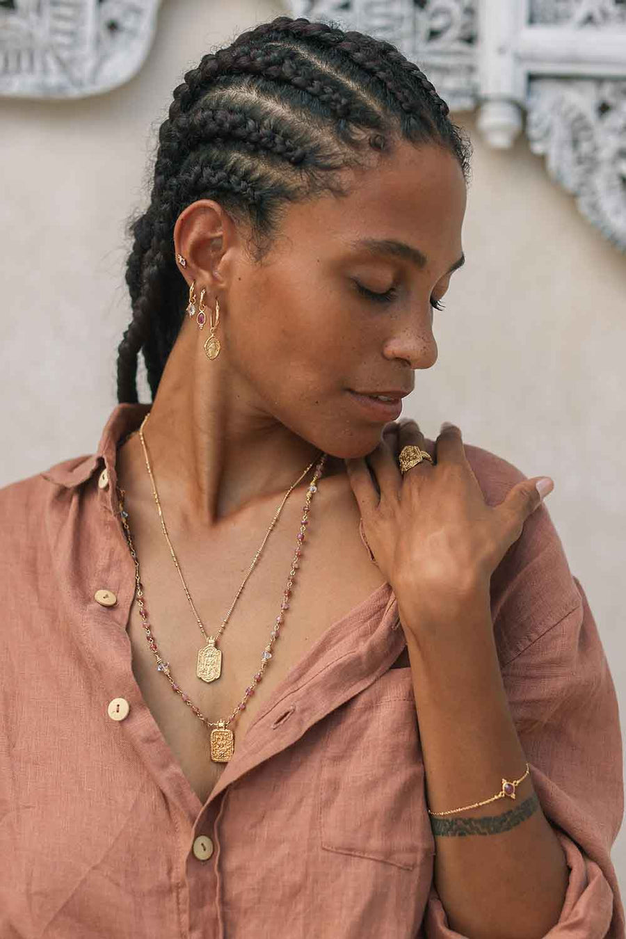 Woman wearing gold jewelry with a neutral background