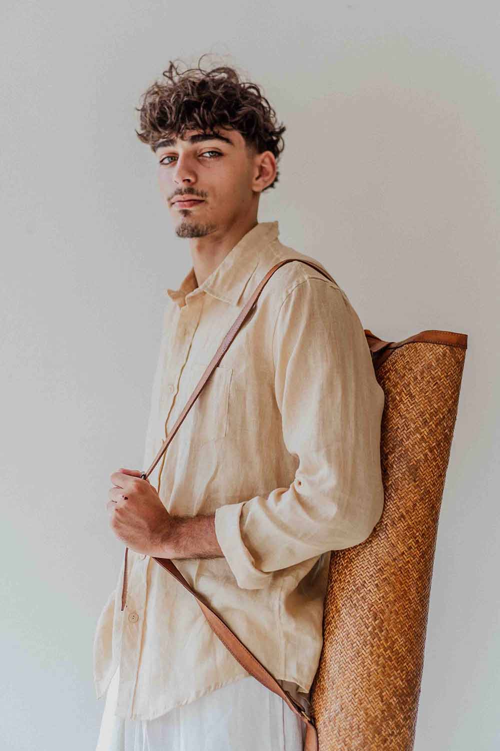 Man holding a woven chair against a plain background