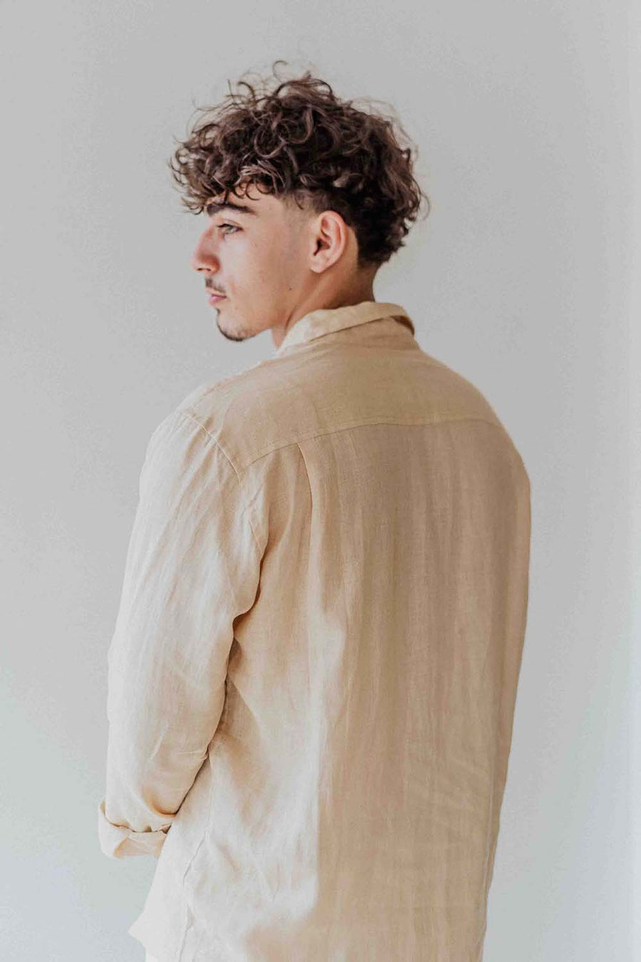 Man wearing a beige shirt against a plain background