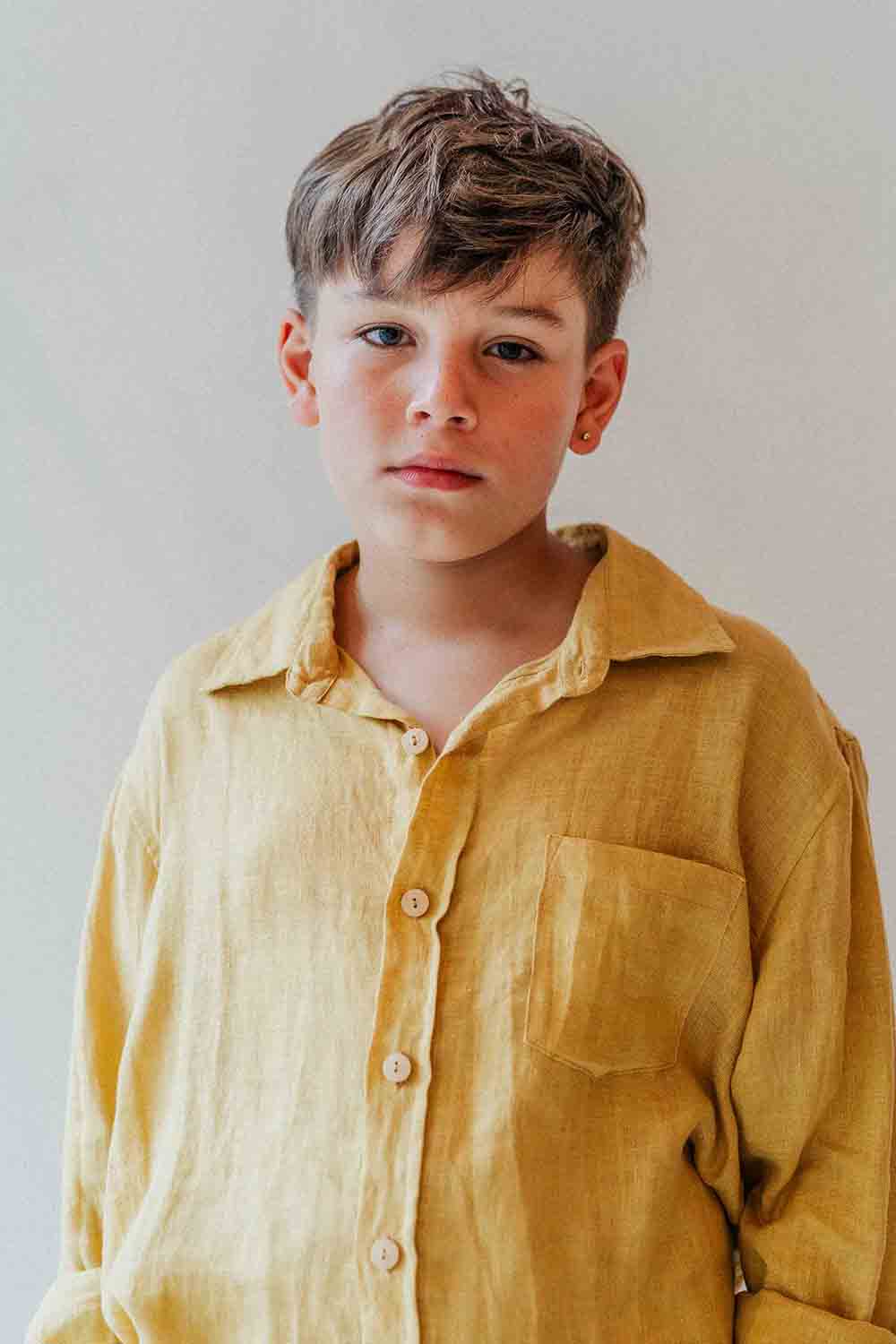 Young boy wearing a yellow shirt against a plain background
