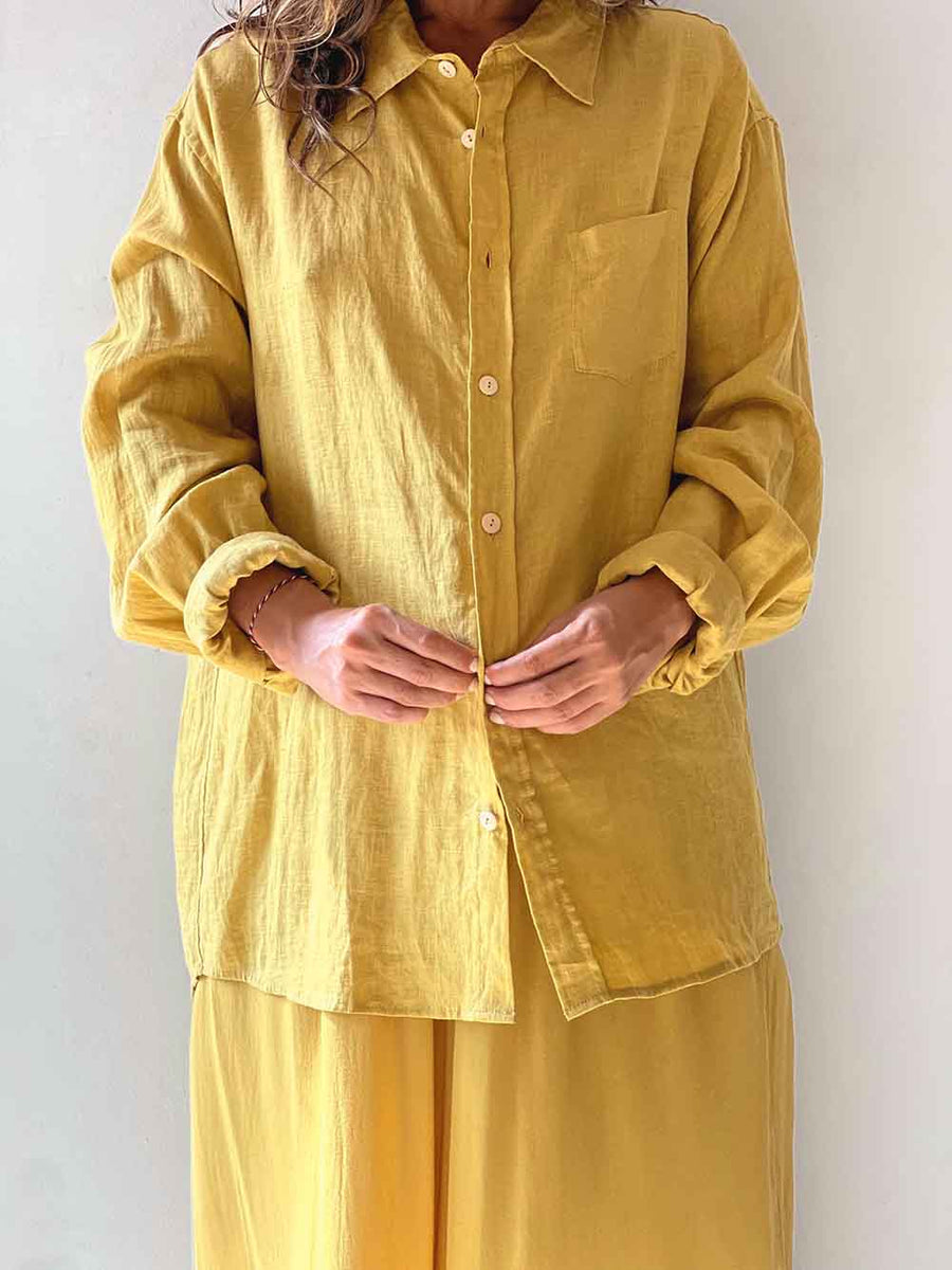 Person wearing a mustard yellow shirt and pants against a white background