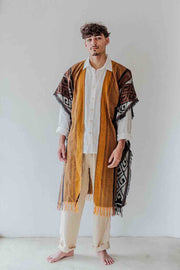 Man wearing a traditional outfit with a patterned shawl on a white background