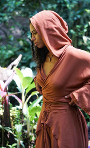 Woman wearing a brown hooded dress in a garden setting
