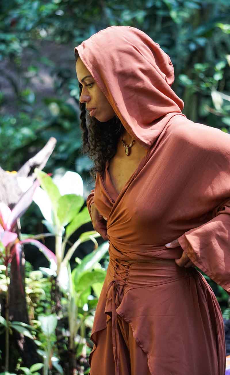 Woman wearing a brown hooded dress in a garden setting