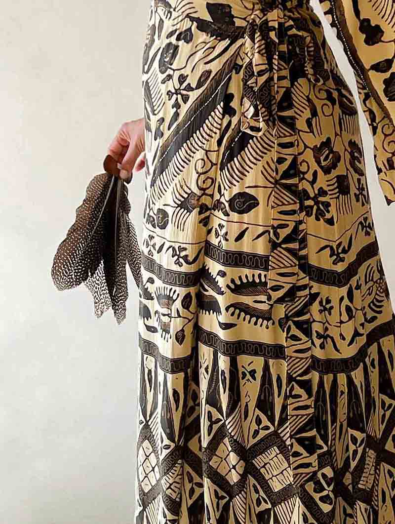 Person wearing a long, patterned dress with a neutral background