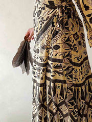 Person wearing a long, patterned dress with a neutral background