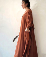 Woman wearing a long rust-colored dress against a plain background