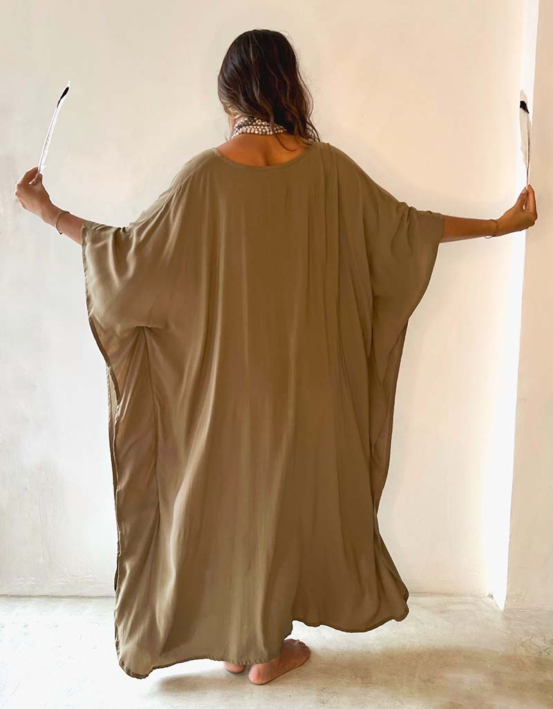 Person wearing a long, light brown dress against a white background