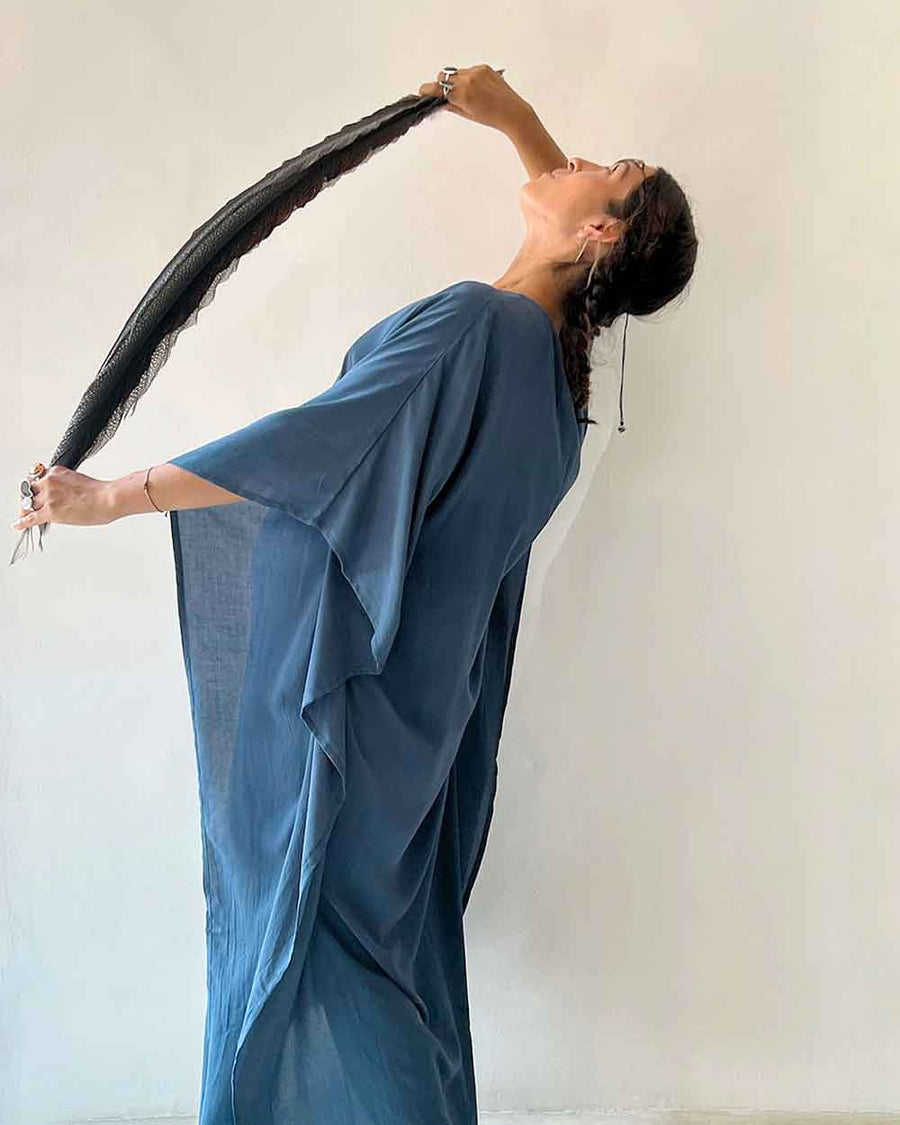 Woman in a blue saree holding a black hairbrush against a white background