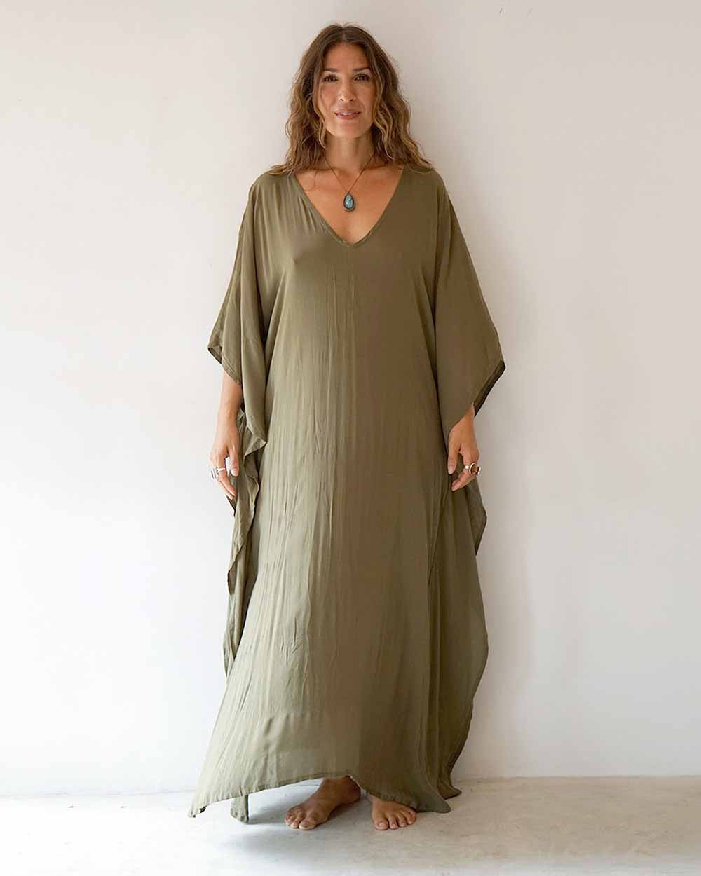 Woman wearing a long olive green dress against a white background