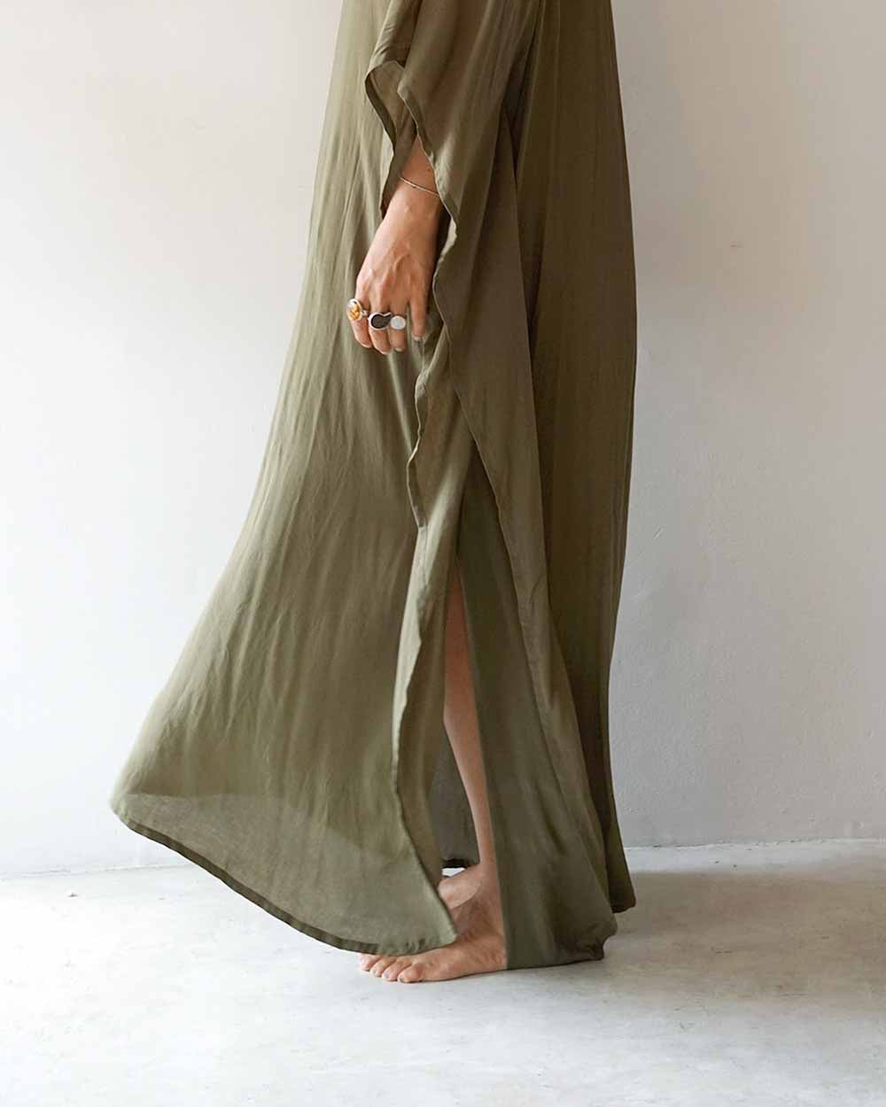 Person wearing a long olive green dress against a plain background