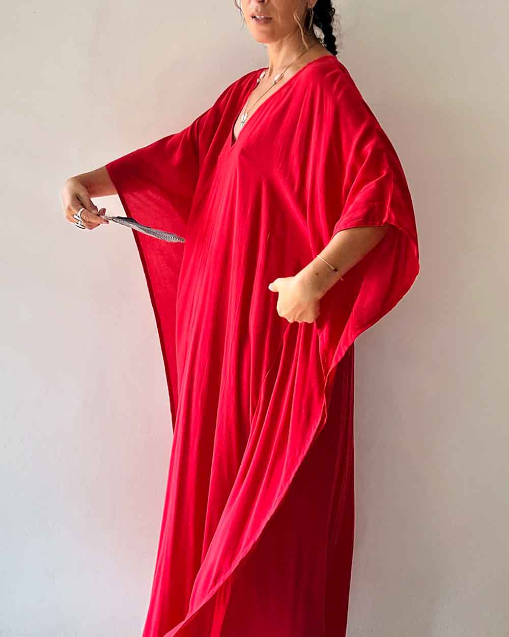 Person wearing a red dress holding a knife against a plain background