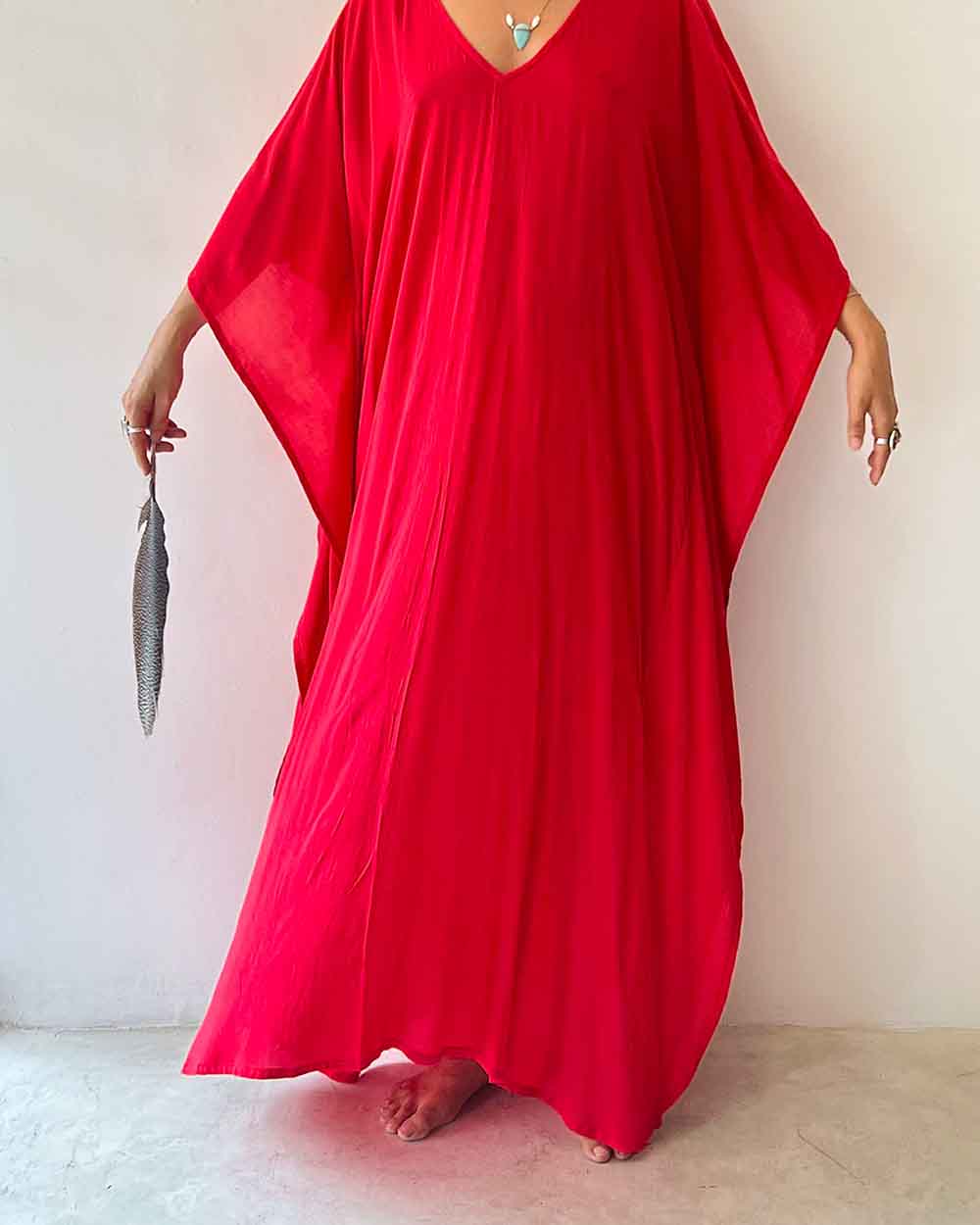 Person wearing a red dress holding a silver clutch against a plain background