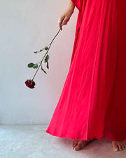 Person wearing a bright red dress holding a wilting red rose against a white background