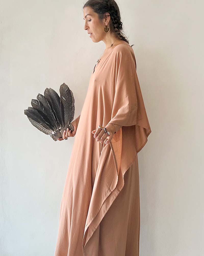 Woman in a peach dress holding a decorative fan against a plain background