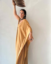 Woman in a mustard yellow dress holding a woven basket against a plain background