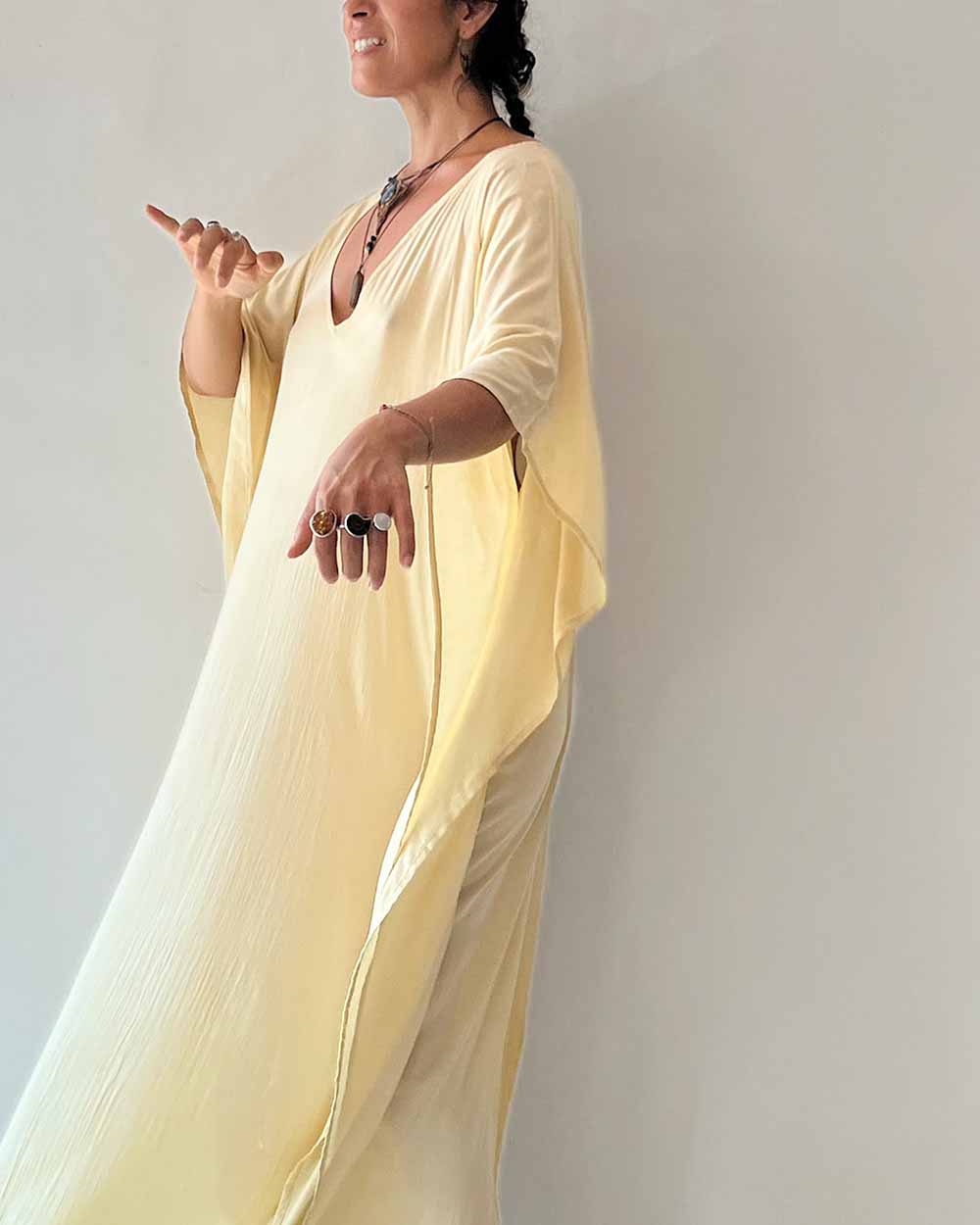 Woman wearing a light yellow dress against a plain background