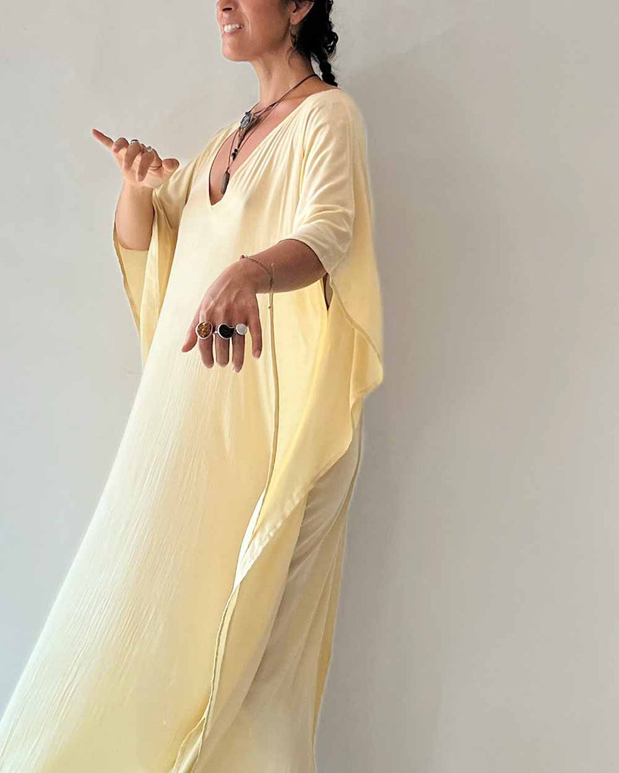 Woman wearing a light yellow dress against a plain background
