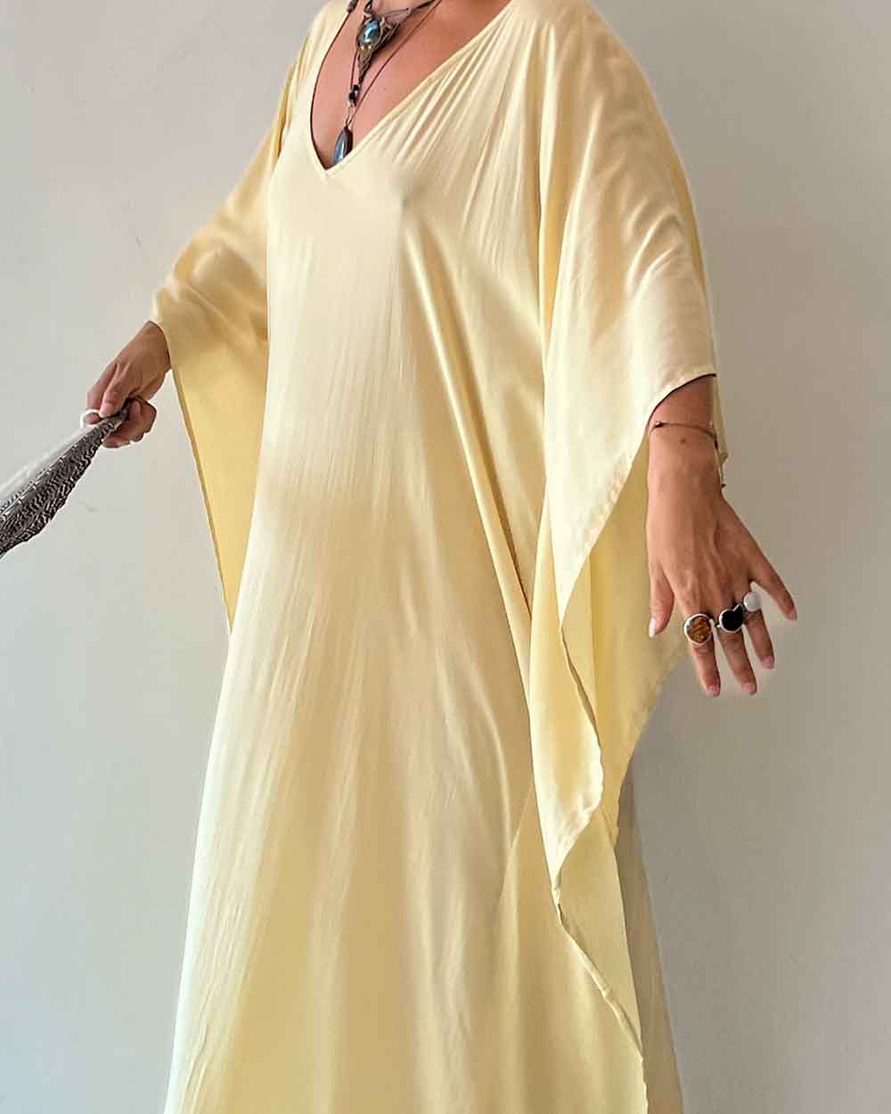 Person wearing a light yellow dress against a plain background