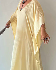 Person wearing a light yellow dress against a plain background