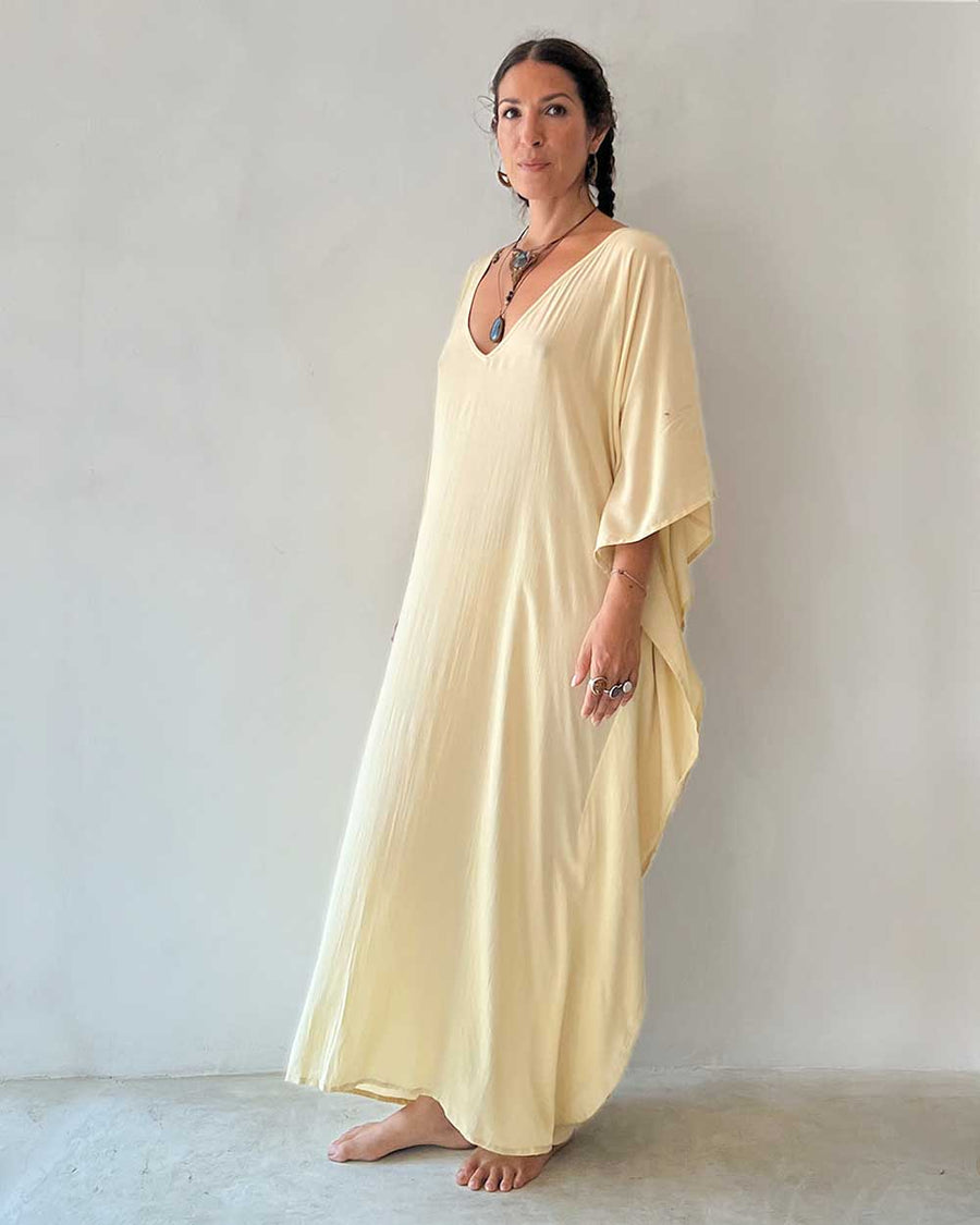 Woman wearing a light yellow dress against a plain background