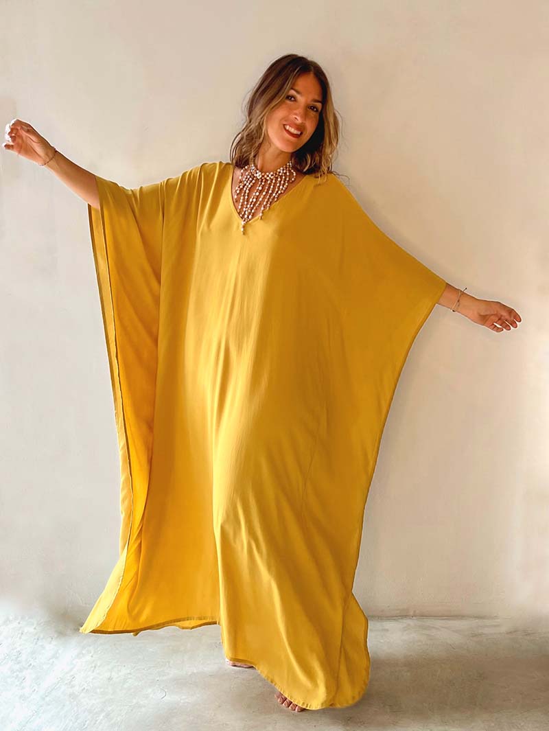 Woman wearing a mustard yellow dress with a plain background