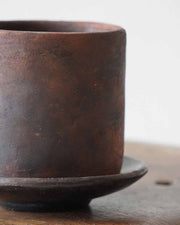 Brown ceramic cup on a matching saucer with a blurred background