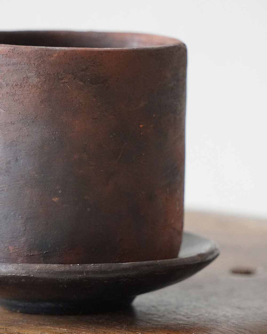 Brown ceramic cup on a matching saucer with a blurred background