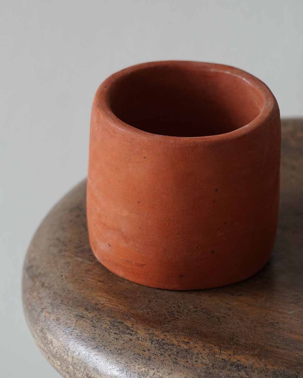 Terracotta cup on a wooden surface with a neutral background