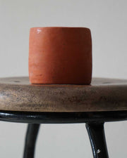 Ceramic pot on a wooden stool with a plain background