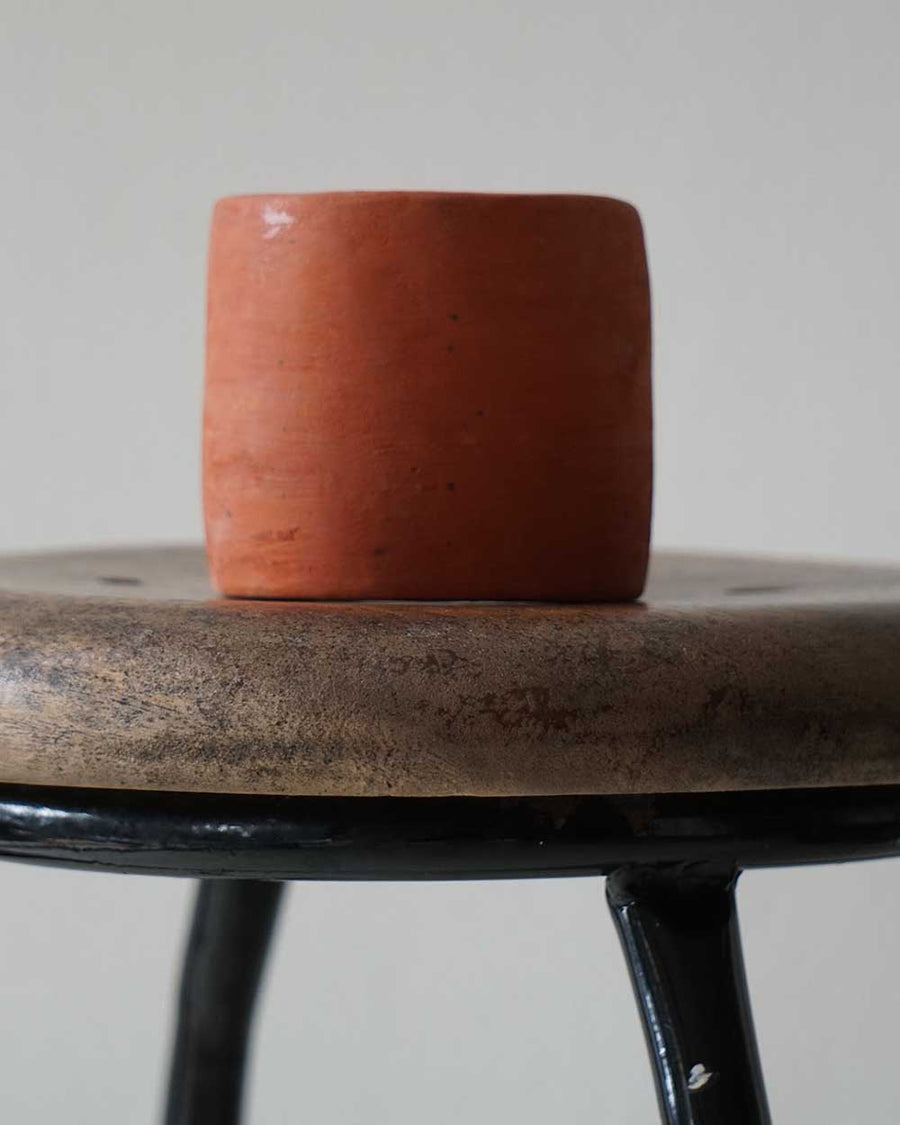 Ceramic pot on a wooden stool with a plain background