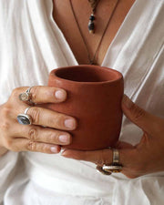 Person holding a terracotta mug with a neutral background
