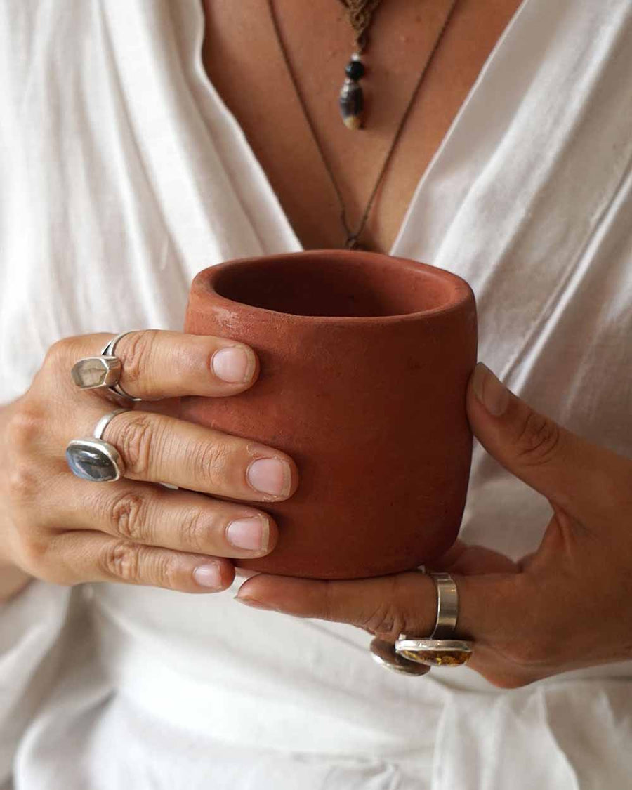 Person holding a terracotta mug with a neutral background