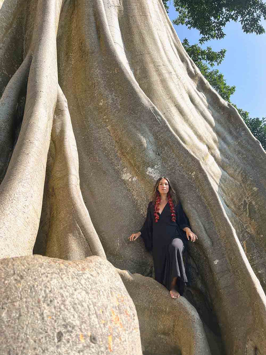 Woman standing inside a large tree with a clear blue sky in the background