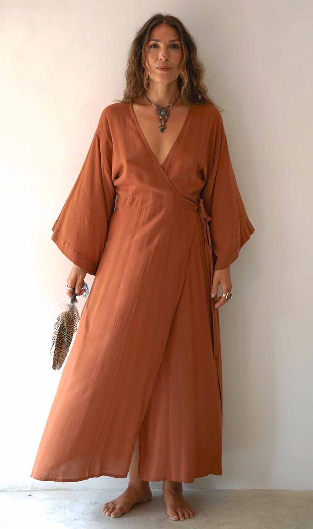 Woman wearing a long rust-colored dress against a plain background