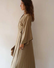 Woman wearing a long beige dress against a plain background