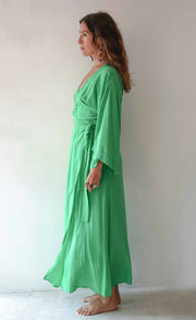Woman wearing a green dress standing against a plain background